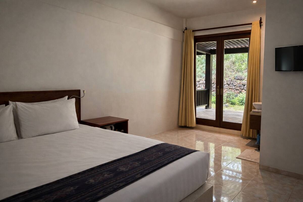 A hotel room with a bed, a nightstand, a TV, and a sliding glass door leading to an outdoor area.