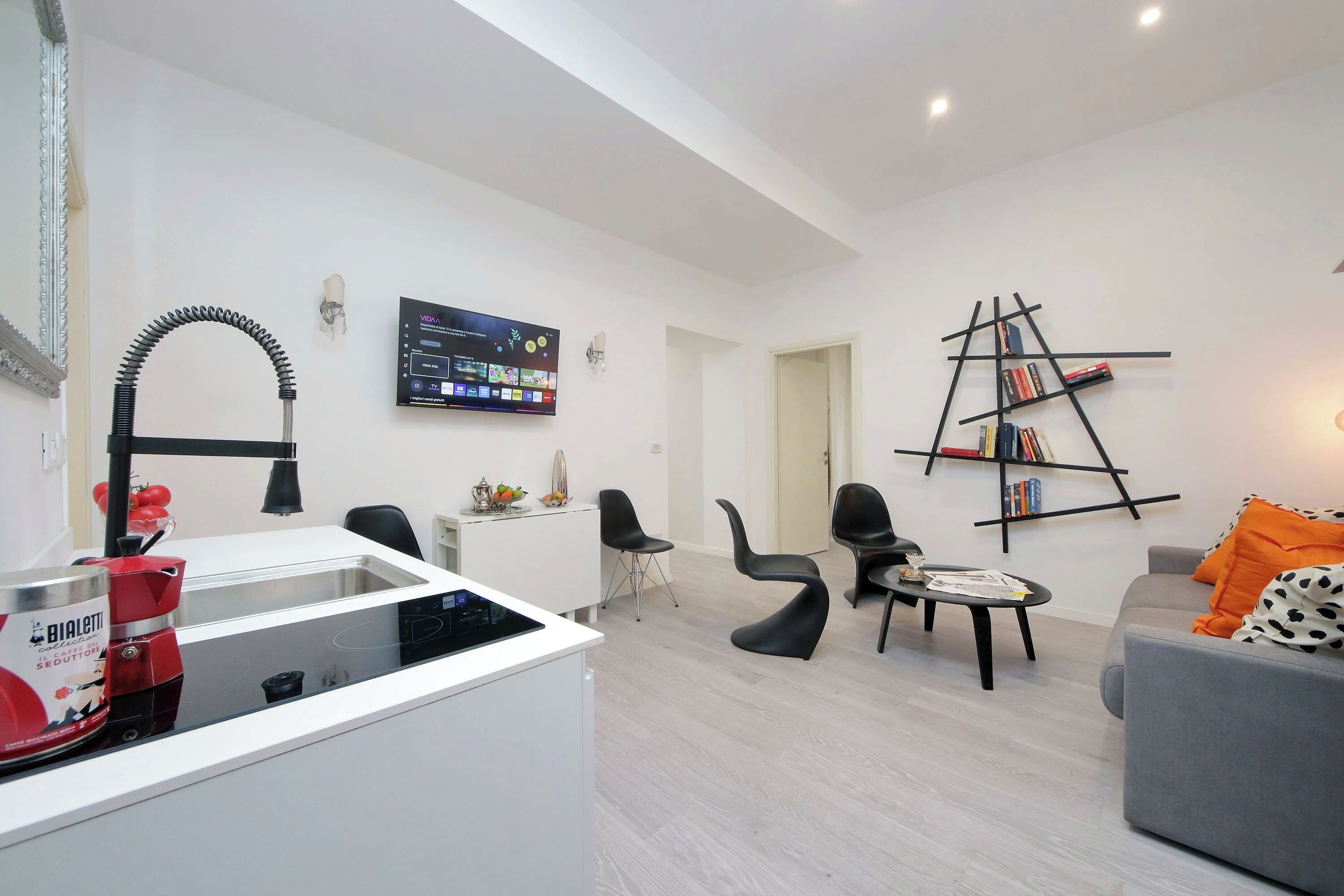 Een moderne woonkamer met een bank, fauteuils, een salontafel, een televisie en een boekenkast.