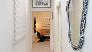 A hallway with a mirror, a framed picture, a sofa with a cushion, and a sign with 'PRAD' text. - 2BR 2BA Historic Center, Metro - Comfort, Quiet (Rome)