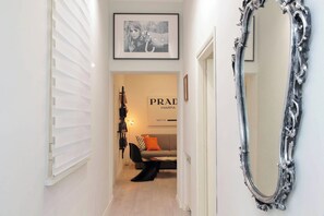 A hallway with a mirror, a framed picture, a sofa with a cushion, and a sign with 'PRAD' text. - 2BR 2BA Historic Center, Metro - Comfort, Quiet (Rome)