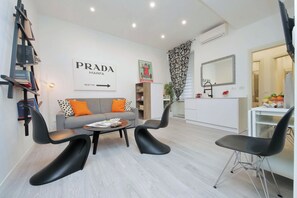 A modern living room with a sofa, two black chairs, a coffee table, and a bookshelf. - 2BR 2BA Historic Center, Metro - Comfort, Quiet (Rome)