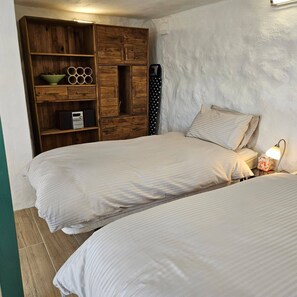A bedroom with two beds, a wooden wardrobe, and a small bedside table with a lamp. - Alba Nueva II Terrace Plus Heated Poolside Apartment (Alhaurin de la Torre)