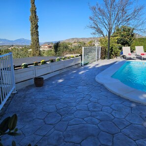 A pool area with a stone patio, a white fence, and a view of mountains. - Alba Nueva II Terrace Plus Heated Poolside Apartment (Alhaurin de la Torre)