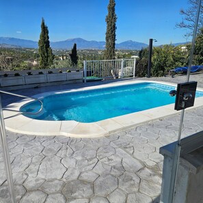 A swimming pool with a stone patio, a metal fence, and a view of mountains in the background. - Alba Nueva II Terrace Plus Heated Poolside Apartment (Alhaurin de la Torre)