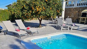 A swimming pool with lounge chairs and a tree with orange fruit. - Alba NEW I Terrace View & Heated Pool (Alhaurin de la Torre)