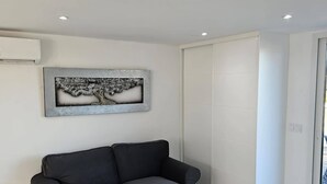 A modern living room with a grey sofa, a wall-mounted artwork, a sliding door closet, and a tiled floor. - Alba NEW I Terrace View & Heated Pool (Alhaurin de la Torre)