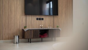 Una sala de estar moderna con un televisor de pantalla plana montado en una pared de madera, una consola minimalista con objetos decorativos y un cubo de basura.