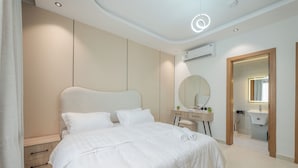 Un dormitorio moderno con una cama grande, un tocador con espejo y un equipo de aire acondicionado.