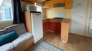 A compact kitchen with a refrigerator, microwave, stove, and wooden cabinets. - Mobile Home for 4–6 Guests – 5 Minutes from the Beach, Châtelaillon-Plage (Châtelaillon-Plage)