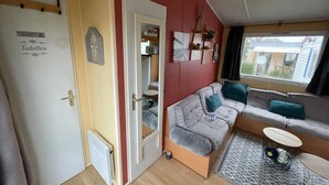 A cozy room with a sofa, a small table, a radiator, and a door labeled 'Toilettes'. - Mobile Home for 4–6 Guests – 5 Minutes from the Beach, Châtelaillon-Plage (Châtelaillon-Plage)