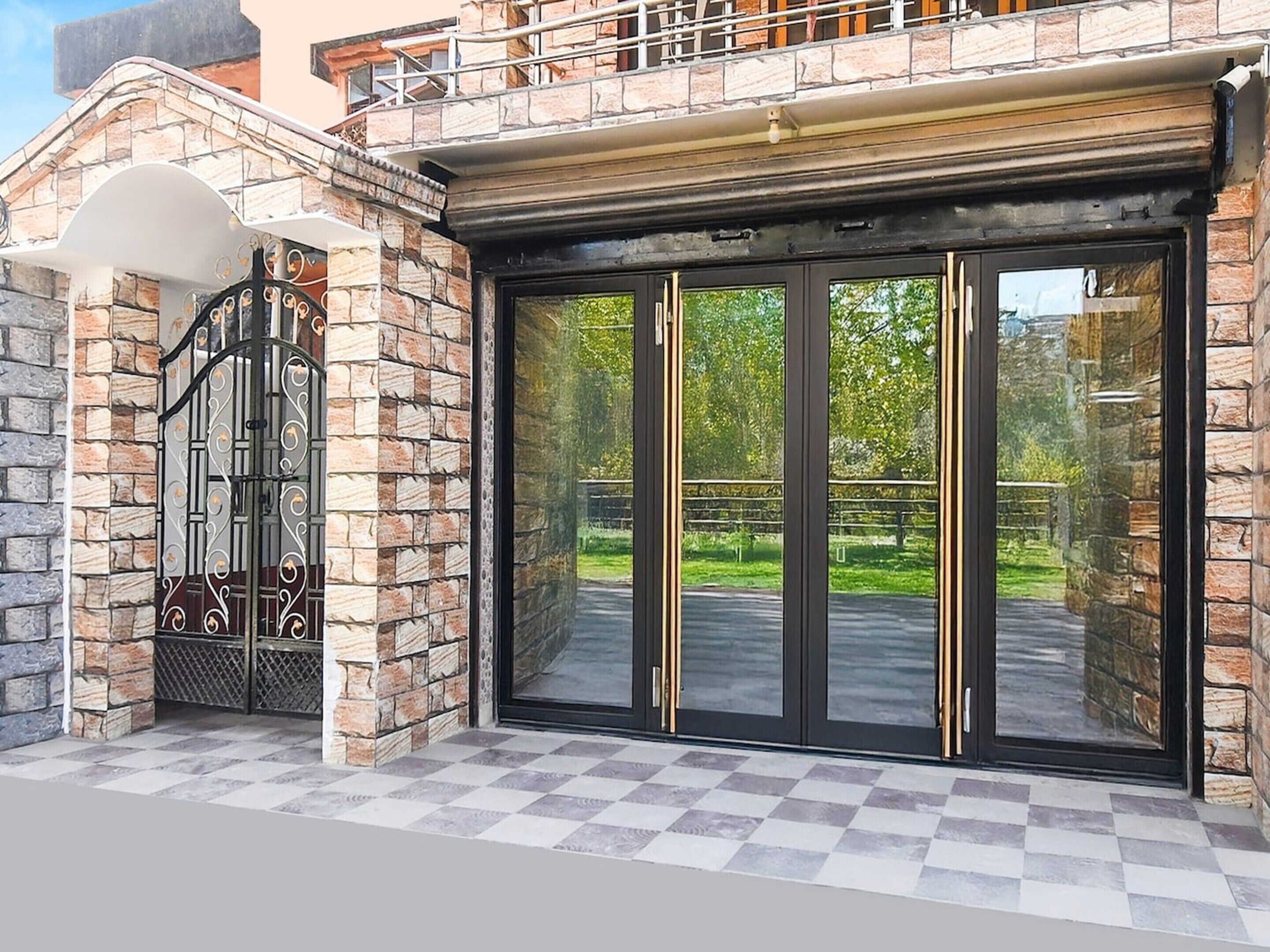 A building entrance with a stone facade, a metal gate, and a large glass door.