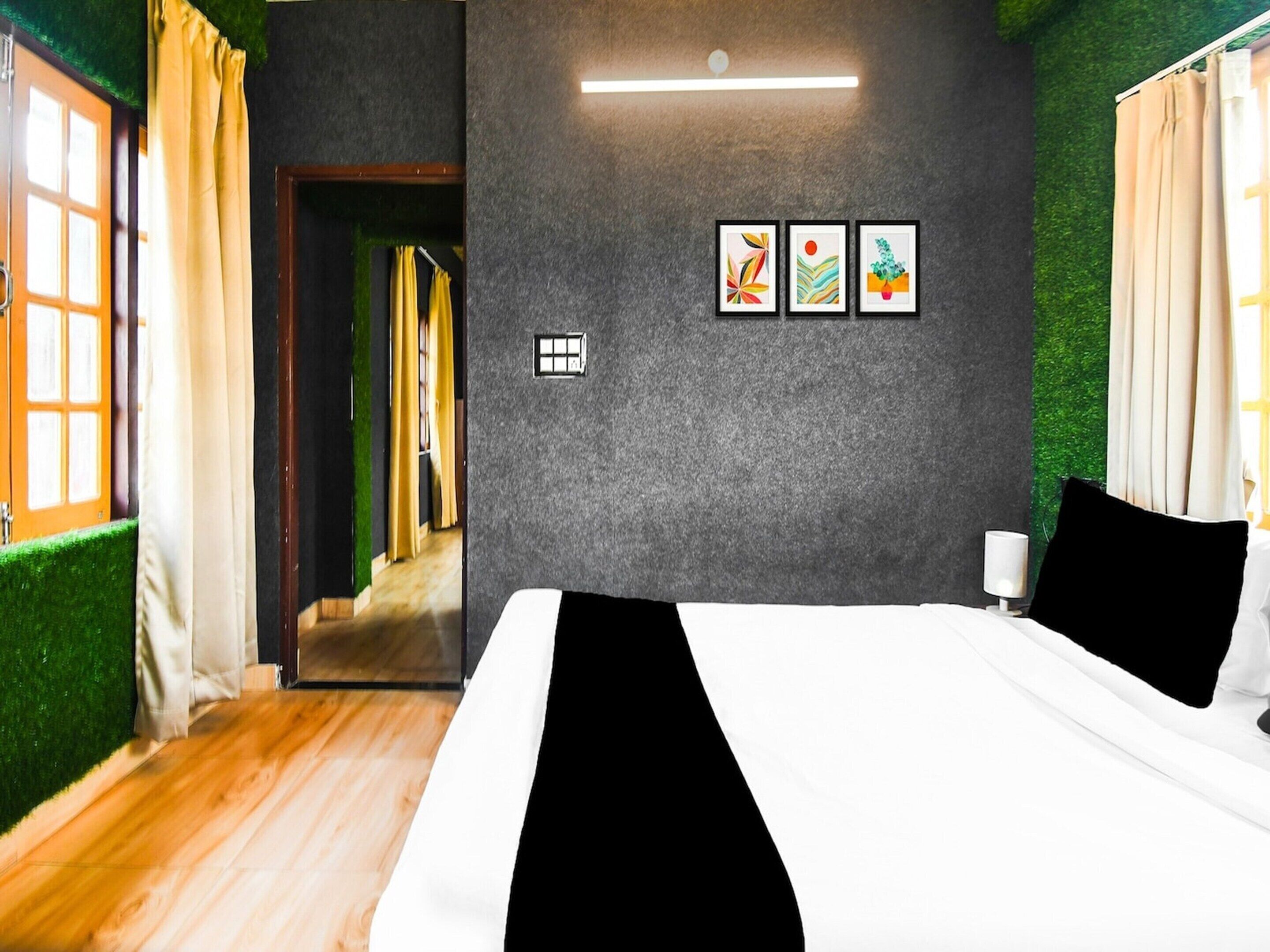 A bedroom with a bed, a bedside table, a lamp, and a window with curtains.