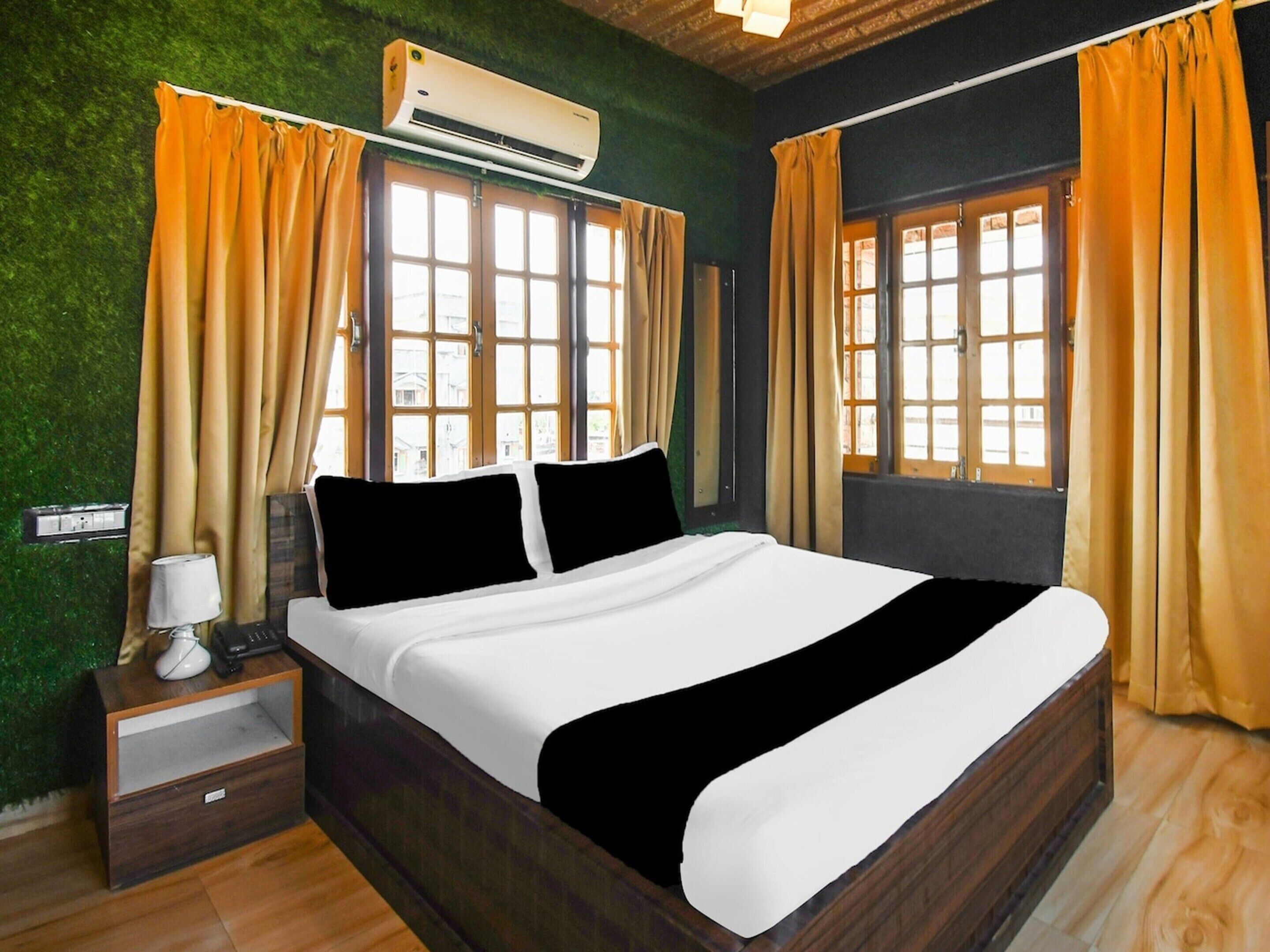 Un dormitorio con cama, cortinas, aire acondicionado y una mesita de noche.