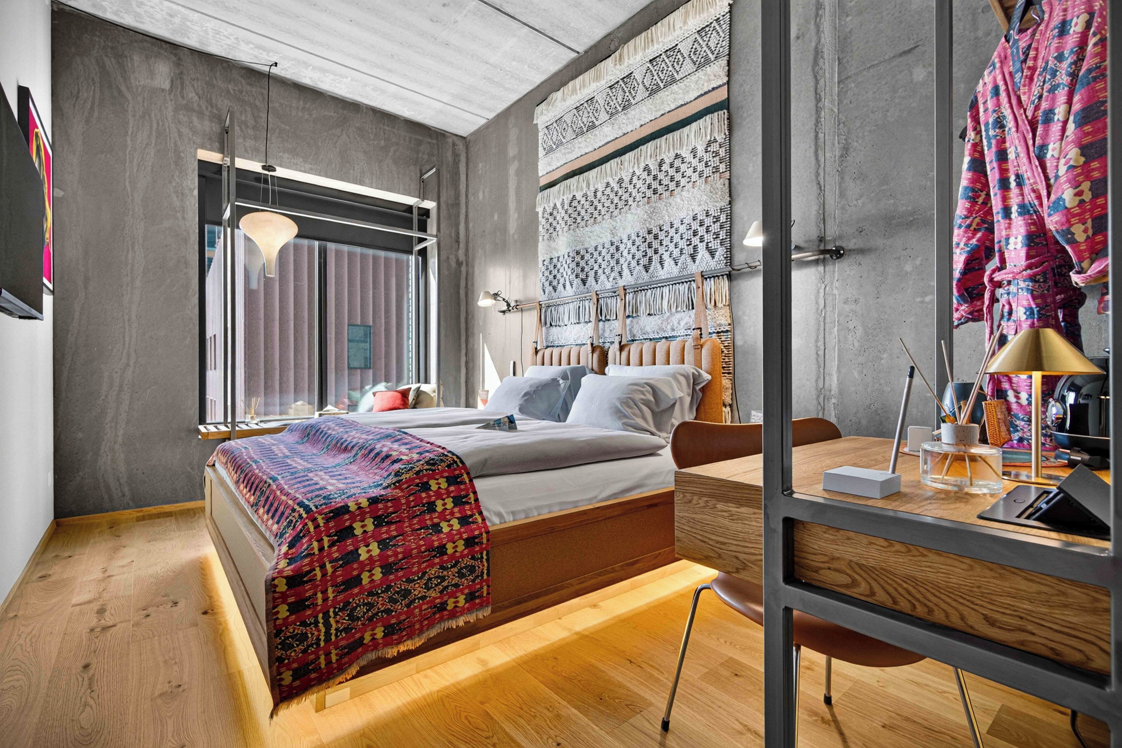 A modern bedroom with a bed, bedside table, and a large window.