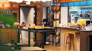 Et moderne restaurantmiljø med højt til loftet, synlige ventilationsrør og en bar.
