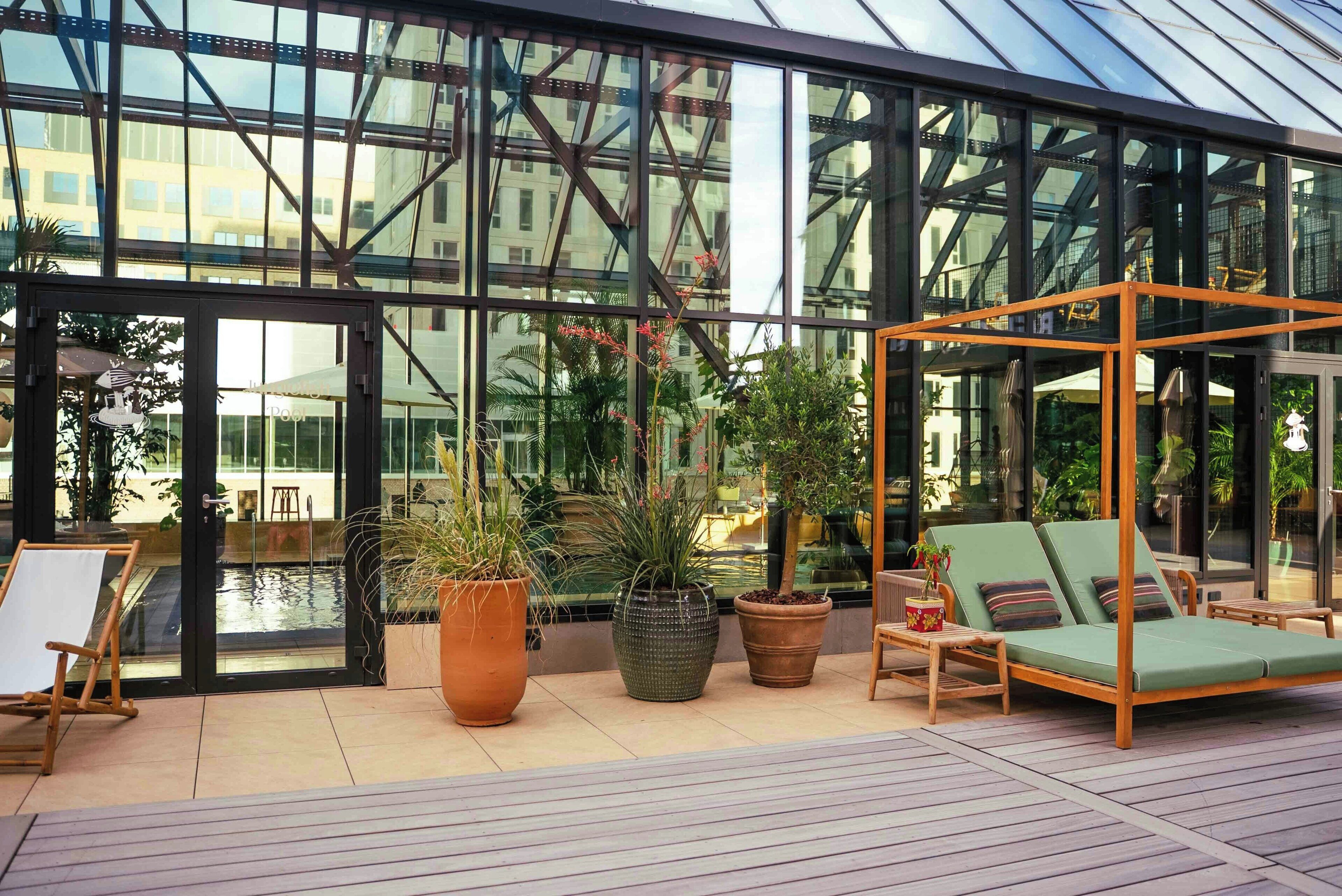 Espaço moderno em ambientes internos, com paredes de vidro, piscina e áreas de estar.