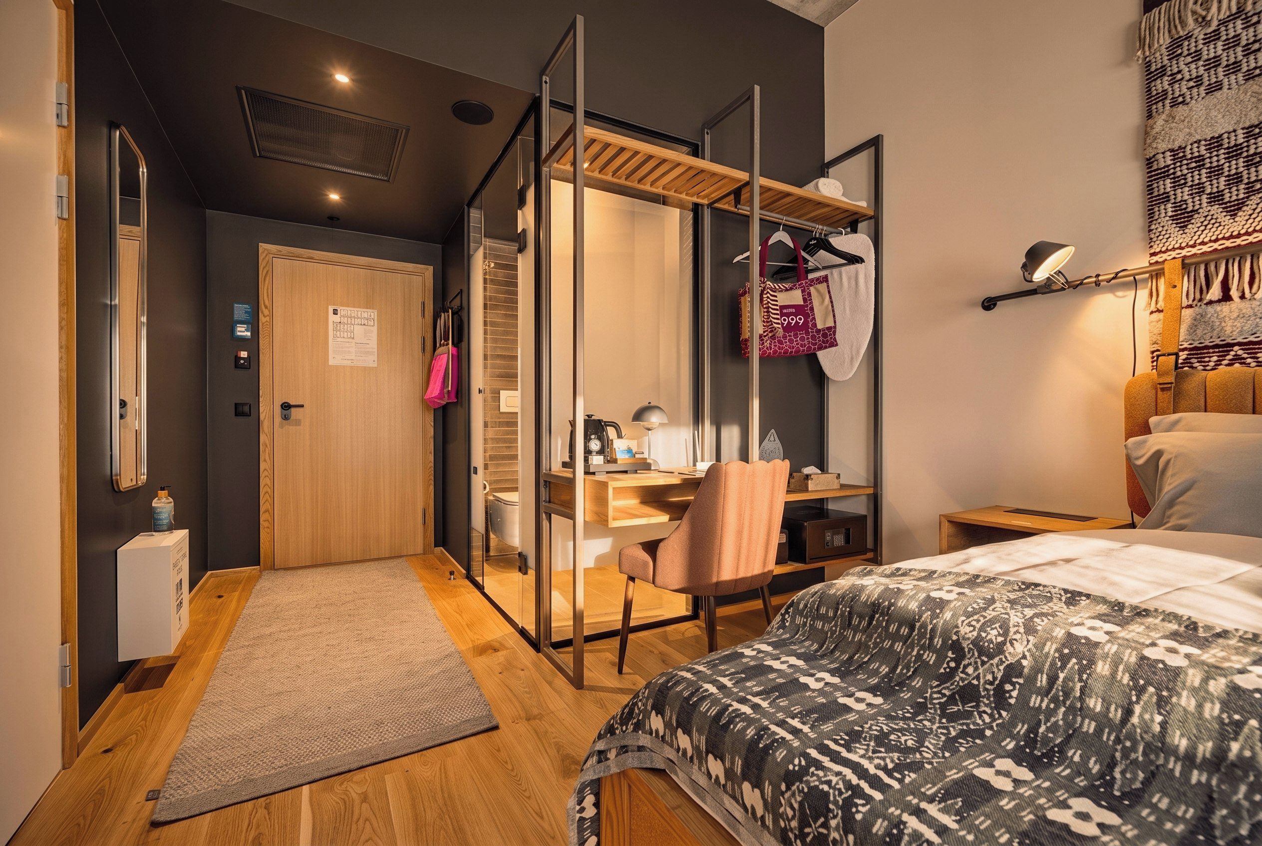 A modern bedroom with a bed, a desk, a chair, a wardrobe, and a bathroom.