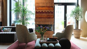 Uma sala de estar moderna com lareira, duas poltronas, uma mesa de centro e um vaso de planta.