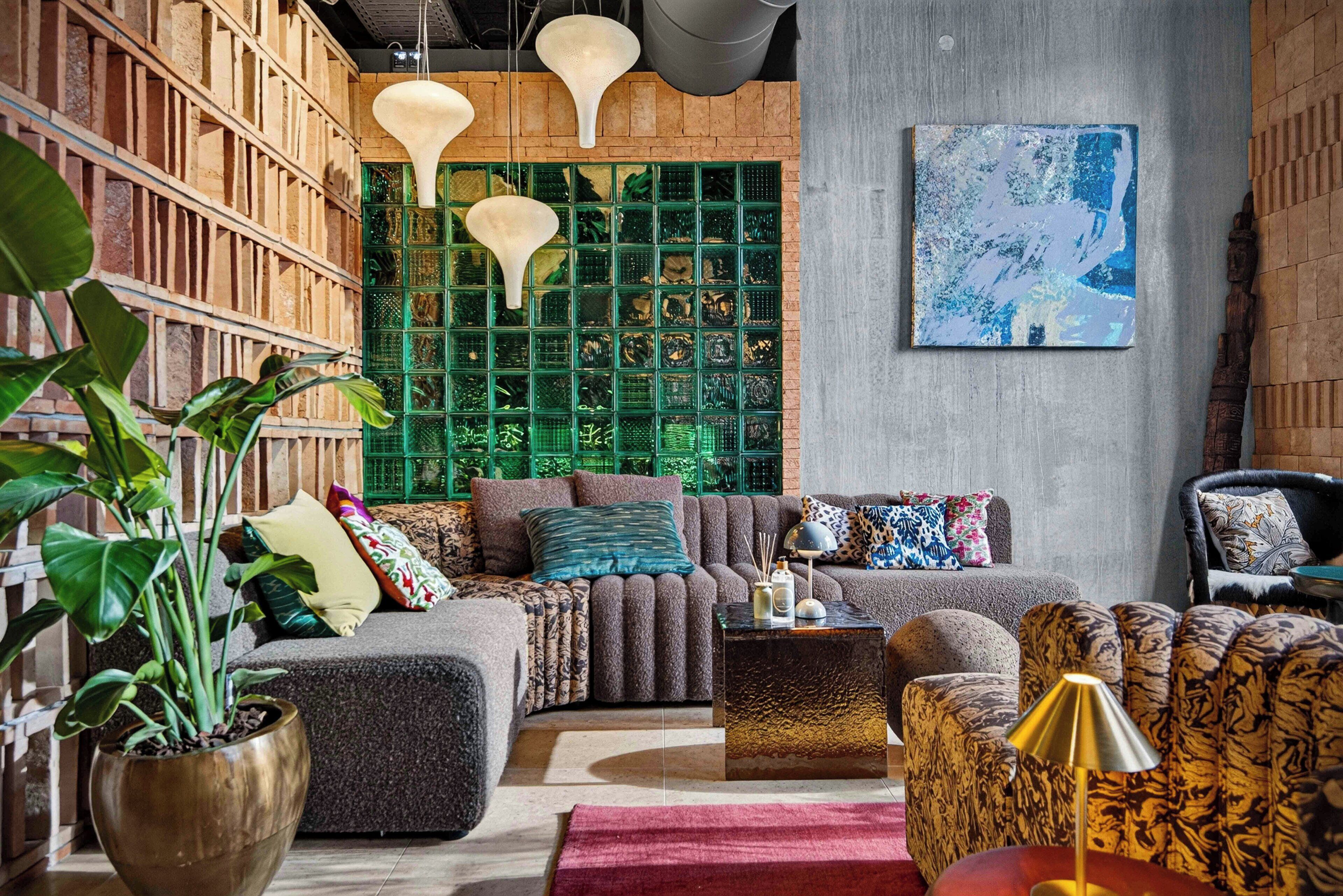 Een moderne woonkamer met een hoekbank, een salontafel en een groene, behang met een patroon.