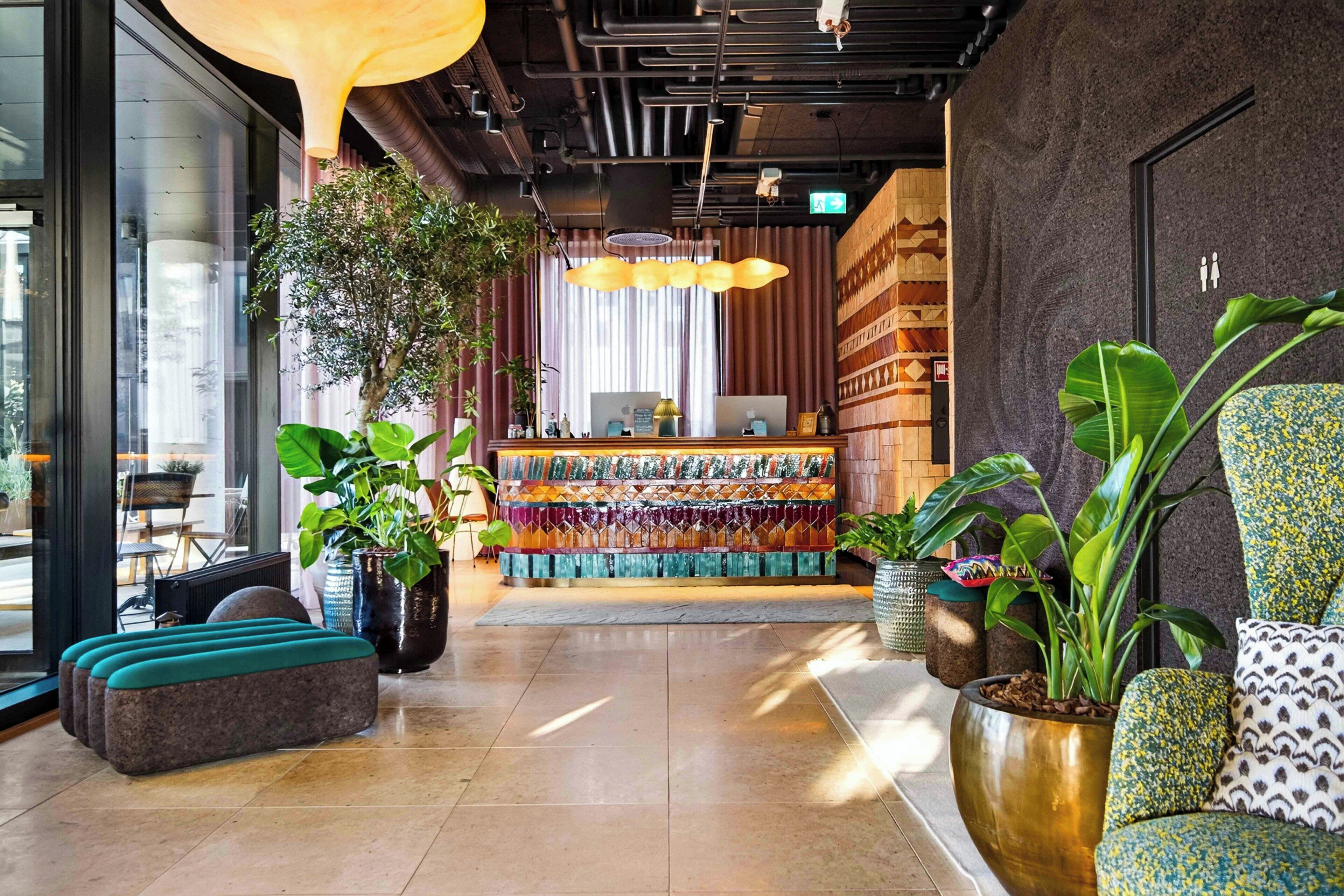 Een moderne lobby met een receptiebalie, een zithoek en potplanten.