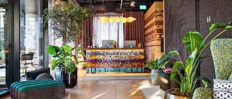 A modern lobby with a reception desk, seating area, and potted plants.