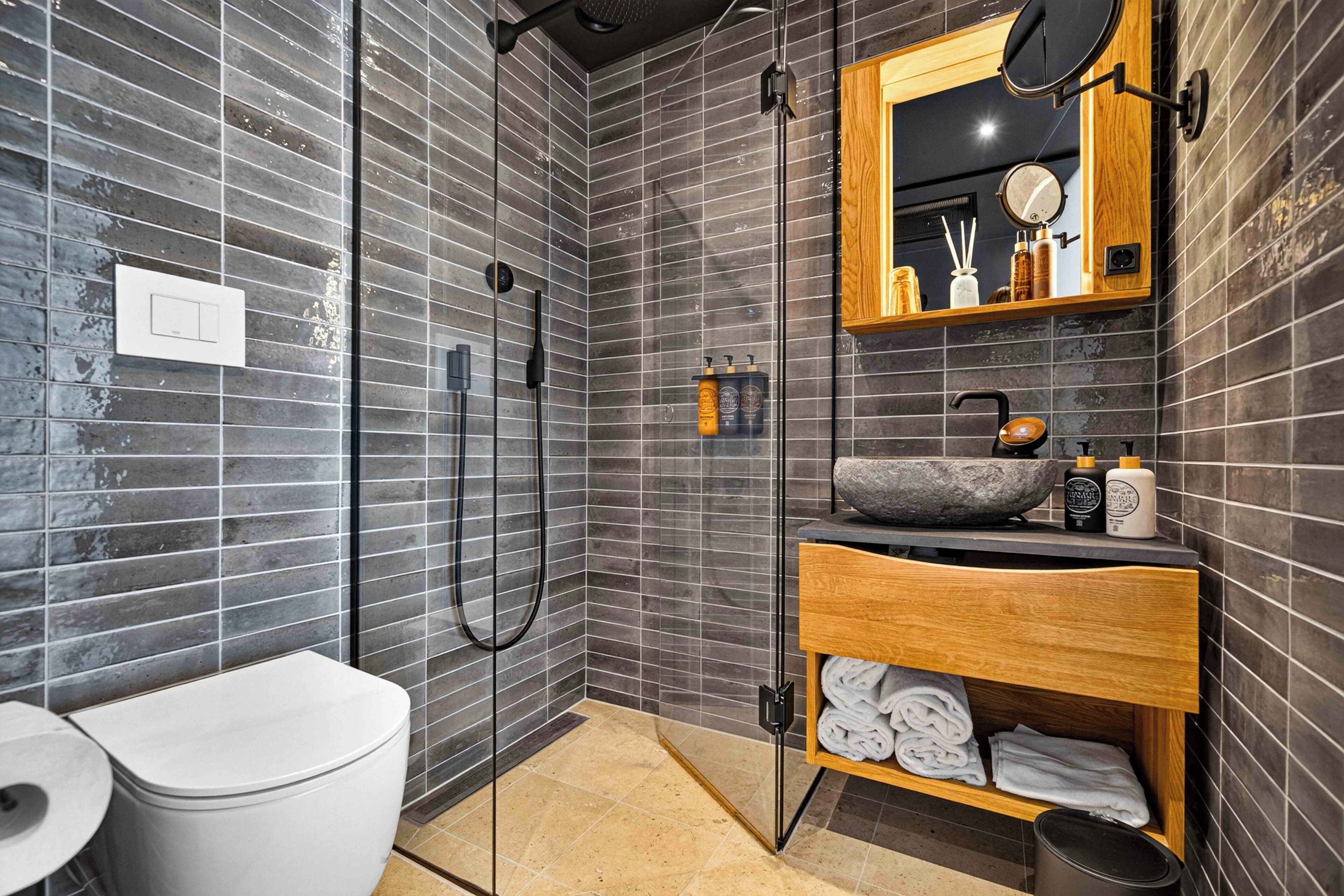 A modern bathroom with a shower, toilet, and vanity with a mirror and toiletries.