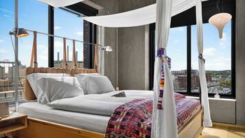 Un dormitorio moderno con cama con dosel, ventanas amplias y vistas a la ciudad.
