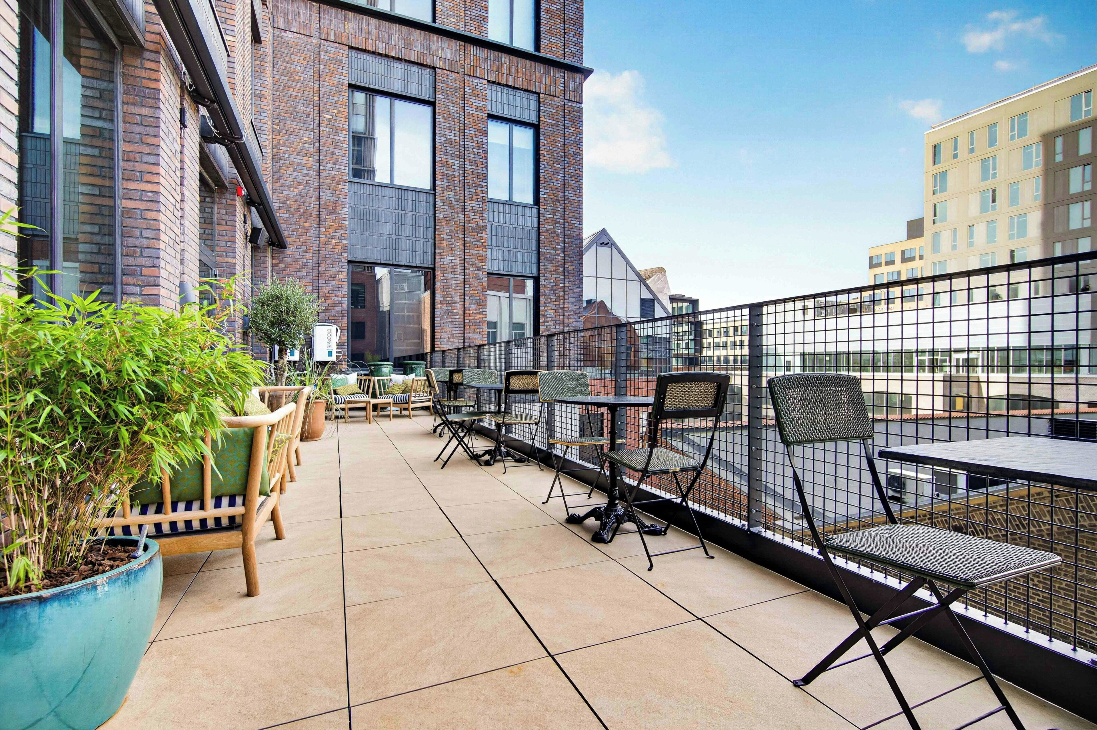 An outdoor terrace with seating and a view of a brick building.