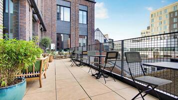 An outdoor terrace with seating and a view of a brick building.