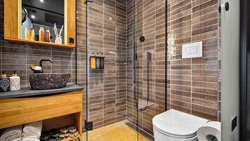 A modern bathroom with a glass shower enclosure, a wooden vanity, and a toilet.