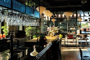 Espaço de bar com adega, luminárias pendentes e vista para a rua.
