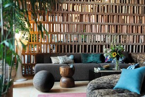 A modern living room with a sofa, a round wooden table, and a decorative wall panel. - Belle Guldsmeden (Aarhus)
