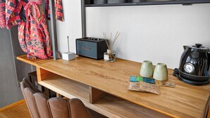 Uma secretária de madeira com um rádio, incenso e uma chaleira.