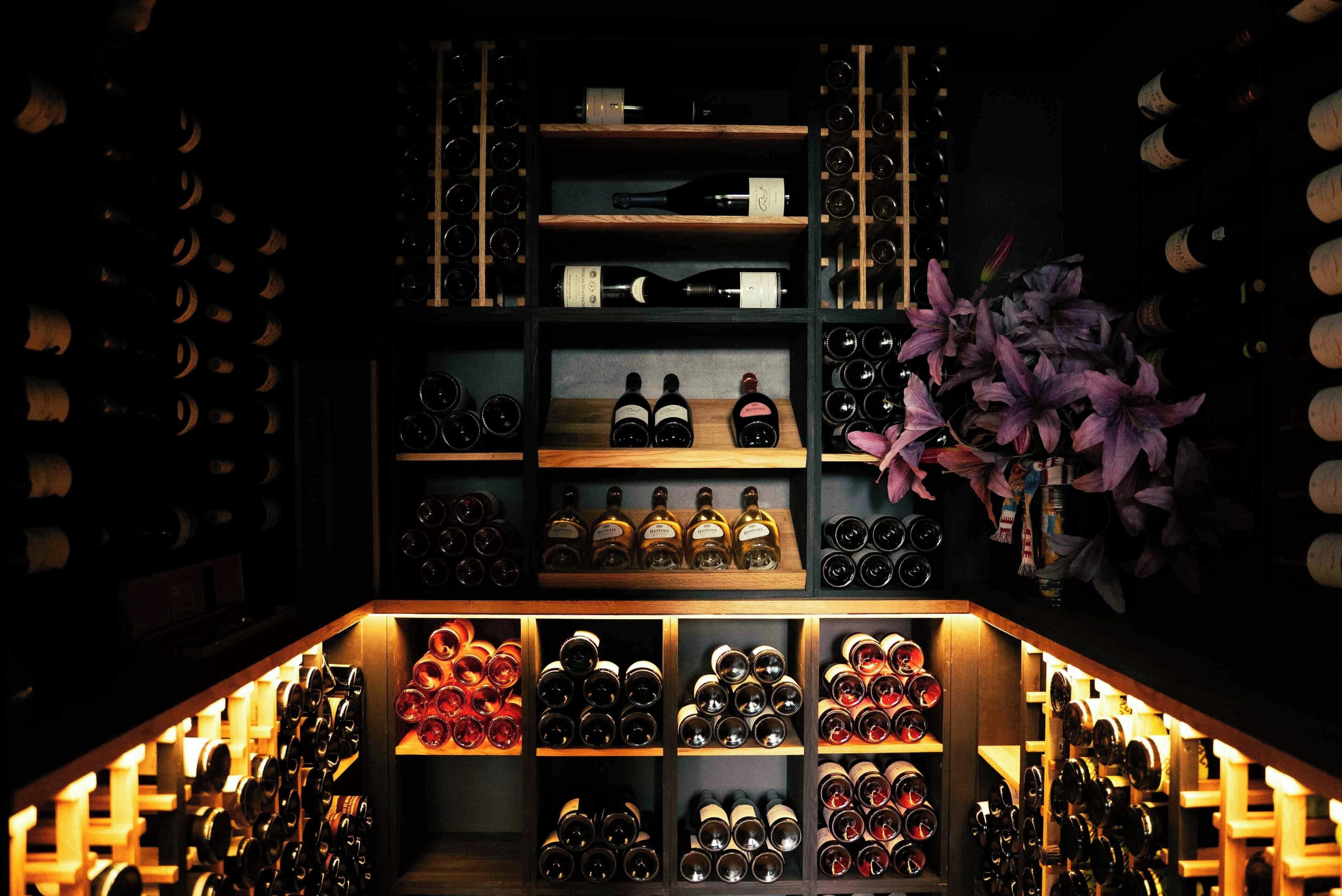 Une cave à vin avec des étagères remplies de bouteilles de vin et de verres.