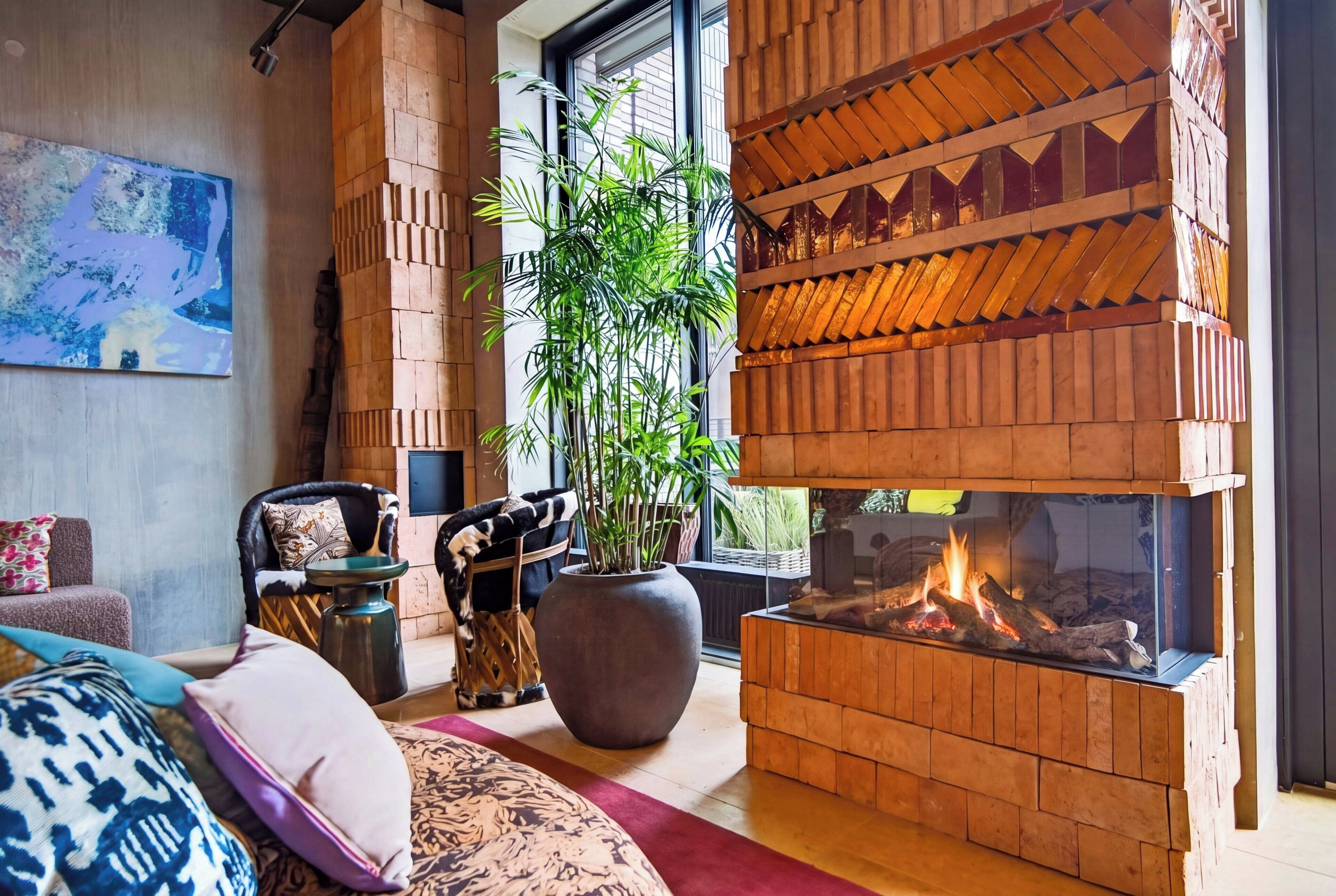 Una sala de estar acogedora con chimenea de ladrillo, una planta grande en maceta y asientos cómodos.