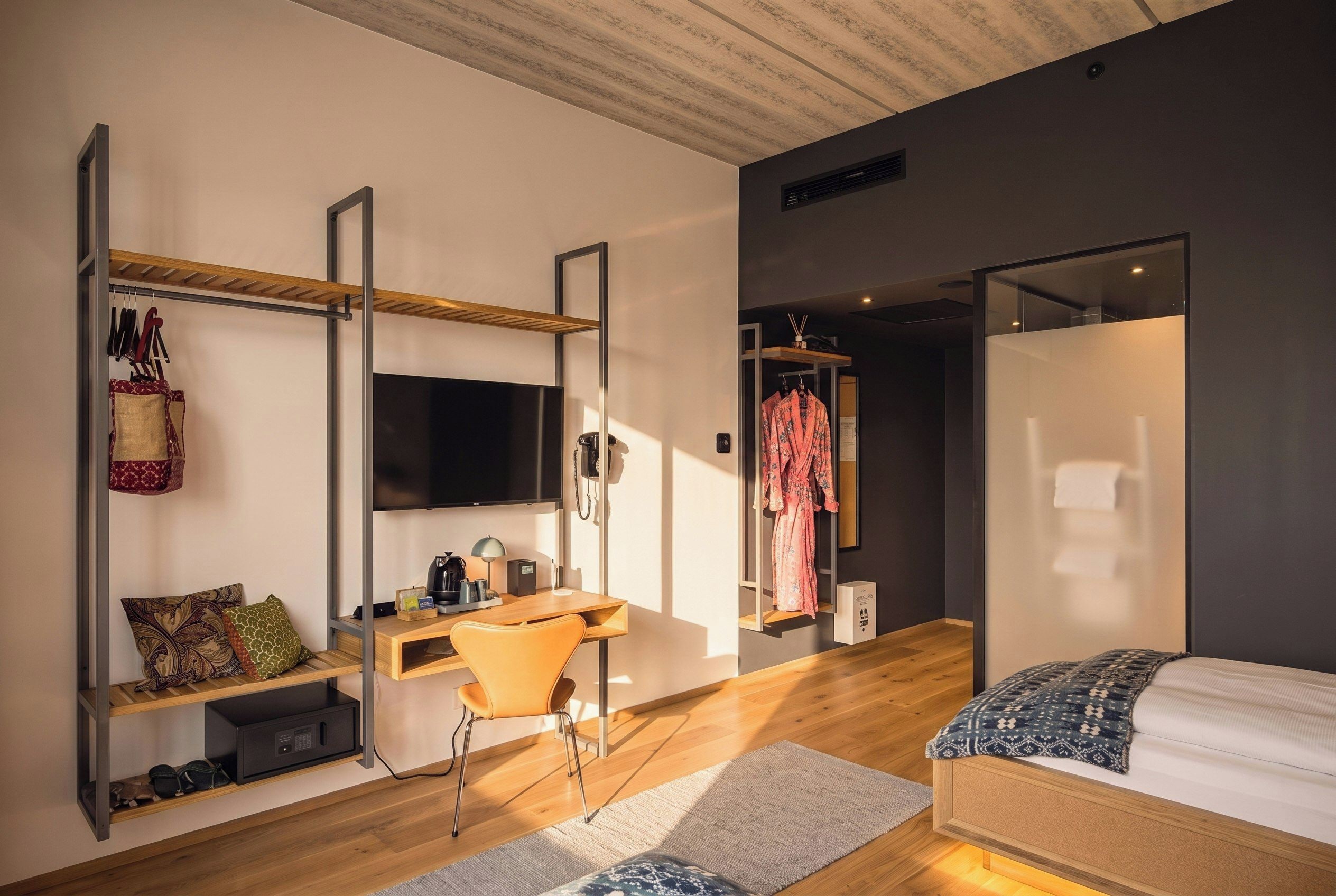 A modern bedroom with a desk, chair, bed, and a wardrobe.
