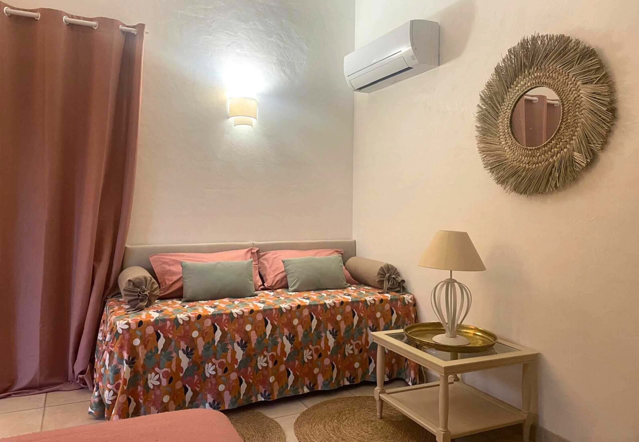 Un dormitorio con cama, mesita de noche con lámpara, aire acondicionado y espejo en la pared.