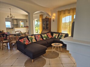 A living room with a sectional sofa, a dining area with chairs, a kitchen in the background, and a staircase leading to another level. - MAGNIFICENT VILLA LES CACTUS WITH PRIVATE POOL (Le Plan-de-la-Tour)