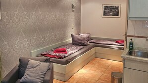 Ein modernes Wohnzimmer mit einer Couch, einem kleinen Tisch, einer Küchenzeile mit Spüle und einer Wand mit Muster.