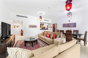 Ein modernes Wohnzimmer mit einer Couch, einem Couchtisch, einem Fernseher und dekorativer Beleuchtung.