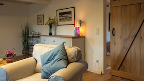 Un salon avec un canapé beige, un meuble en bois, une bibliothèque et une porte en bois.