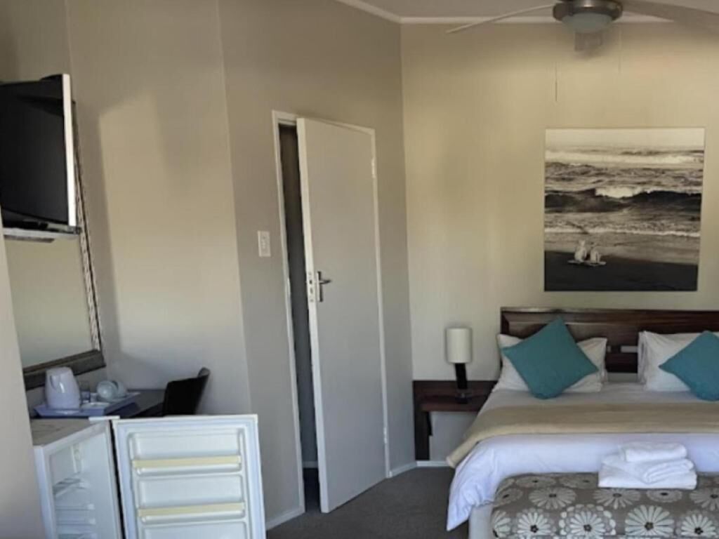 Une chambre d’hôtel avec un lit, un bureau, une télévision, une porte et un tableau au mur.