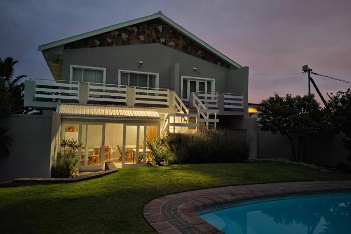 A modern two-story house with a swimming pool, a covered patio, and a well-maintained lawn.