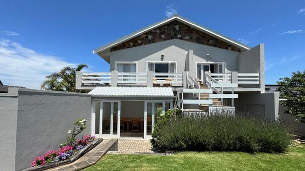 A modern two-story house with a balcony, a covered patio, and a well-maintained lawn. - Moments Guesthouse (Kleinmond)