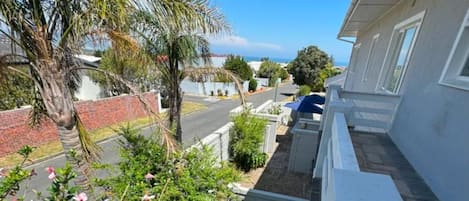 Una calle residencial con casas, una palmera y un cielo azul despejado.