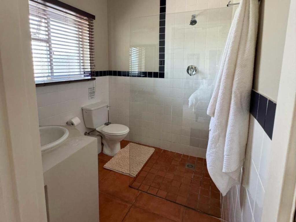 Un bagno con servizi igienici, lavandino, doccia e un asciugamano appeso al muro.