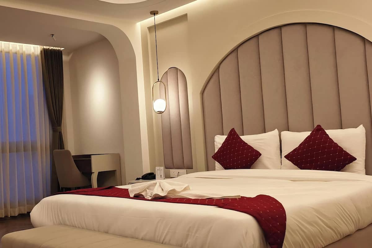 A hotel room with a bed, a desk, a chair, and a large window with curtains.