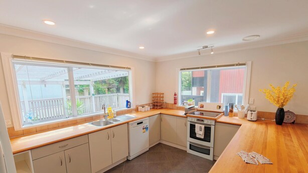 A modern kitchen with a dishwasher, oven, and a wooden countertop. - Botanic Garden Retreat | Sleeps 6 | 3 Ensuite Bedrooms (Wellington)