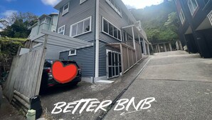 A multi-story building with a garage, a covered porch, and a driveway. - Botanic Garden Retreat | Sleeps 6 | 3 Ensuite Bedrooms (Wellington)
