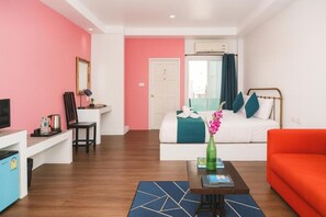 Een kamer met een bed, een bureau, een televisie en een rode bank.